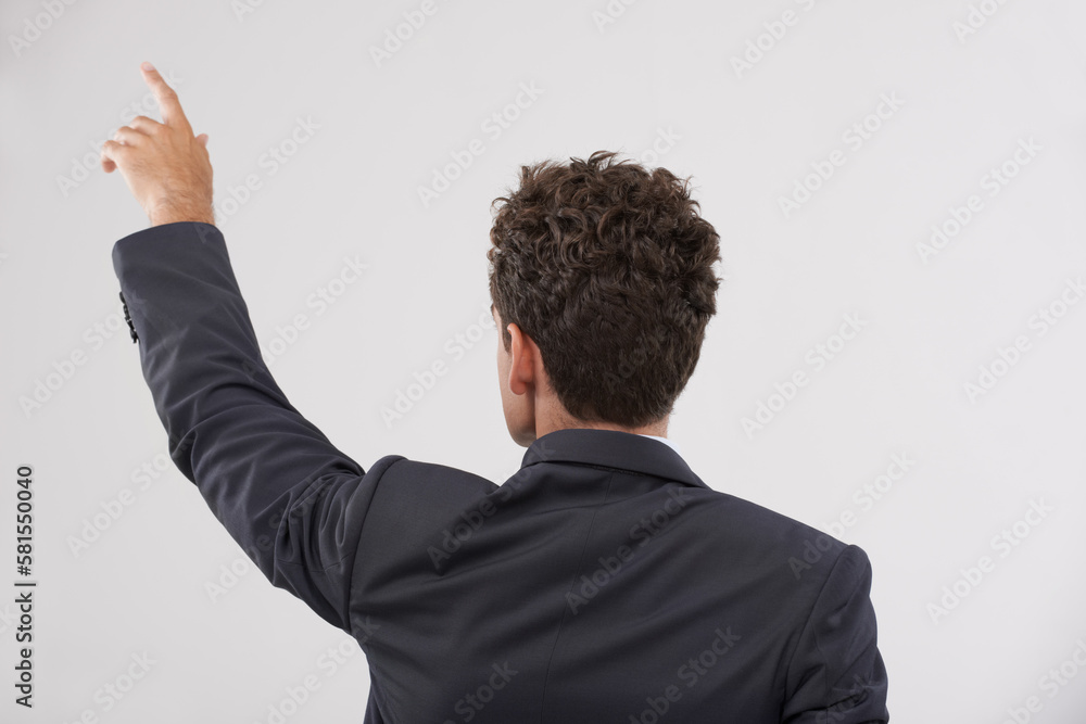 The way to the future is forward. Rear view of a handsome young businessman touching a transparent digital interface. The way to the future is forward. Rear view of a handsome young businessman touching a transparent digital interface.