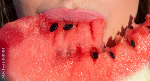 Watermelon in women mouth, close up. Girl eating, watermelon. Macro lips and atermelon. Summer fruits. photo