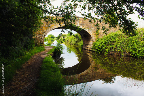 A stunning landscape shot of a bridge over the Leeds and Liverpool canal. The reflection of the bridge can be seen in the water below. © NW_Photographer