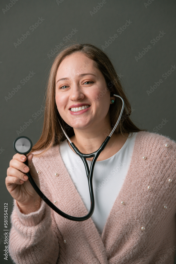 PROFESSIONAL WOMAN: CAUCASIAN LIGHT-EYED MATURE WOMAN, HISPANIC LATINO, PRETTY MOTHER, OVER GRAY BACKGROUND DRESSED IN A DOCTOR'S GOWN AND A STETHOSCOPE, WOMAN DOCTOR, HEALTH AND MEDICINE, HEALTHCARE PROFESSIONAL WOMAN: CAUCASIAN LIGHT-EYED MATURE WOMAN, HISPANIC LATINO, PRETTY MOTHER, OVER GRAY BACKGROUND DRESSED IN A DOCTOR'S GOWN AND A STETHOSCOPE, WOMAN DOCTOR, HEALTH AND MEDICINE, HEALTHCARE