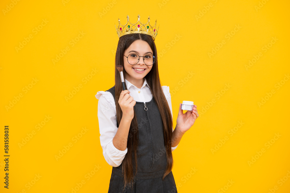 Kid girl in queen crown hold powder and brush for birthday make up on yellow background. Princess girl in tiara.