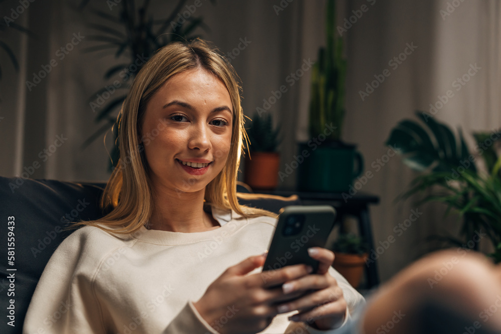 A young woman is using a cellphone and looking at the camera A young woman is using a cellphone and looking at the camera