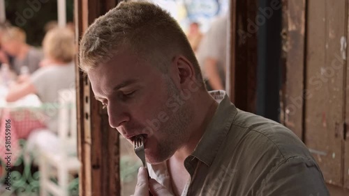 Caucasian middle-aged blond man enjoying eating rare beef steak in authentic restaurant.Person having delicious and tasty meal. photo