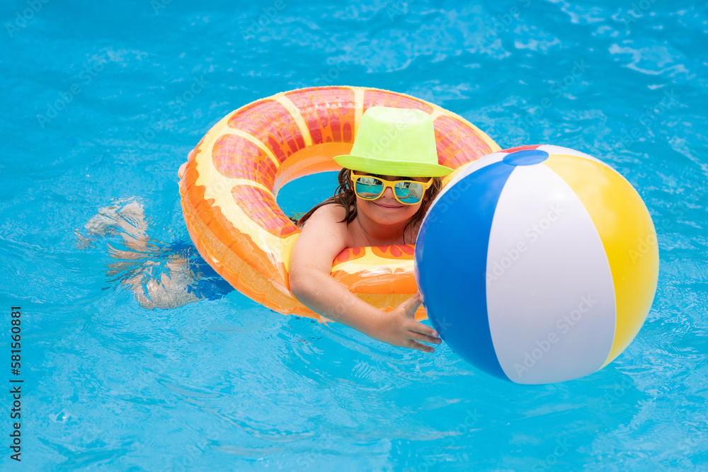 Summertime fun. Child swimming in pool play with floating ring. Smiling cute kid in sunglasses swim with inflatable rings in pool in summer day.