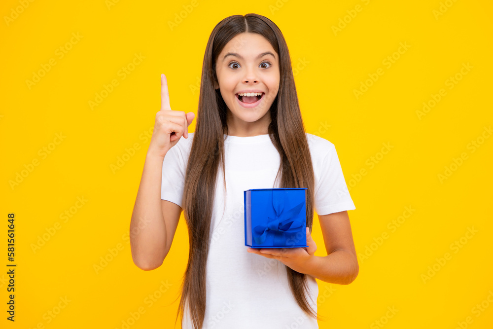 Happy teenager portrait. Smiling girl in t shirt. Teenager child holding gift box on yellow isolated background. Gift for kids birthday. Summer holiday. Happy teenager portrait. Smiling girl in t shirt. Teenager child holding gift box on yellow isolated background. Gift for kids birthday. Summer holiday.