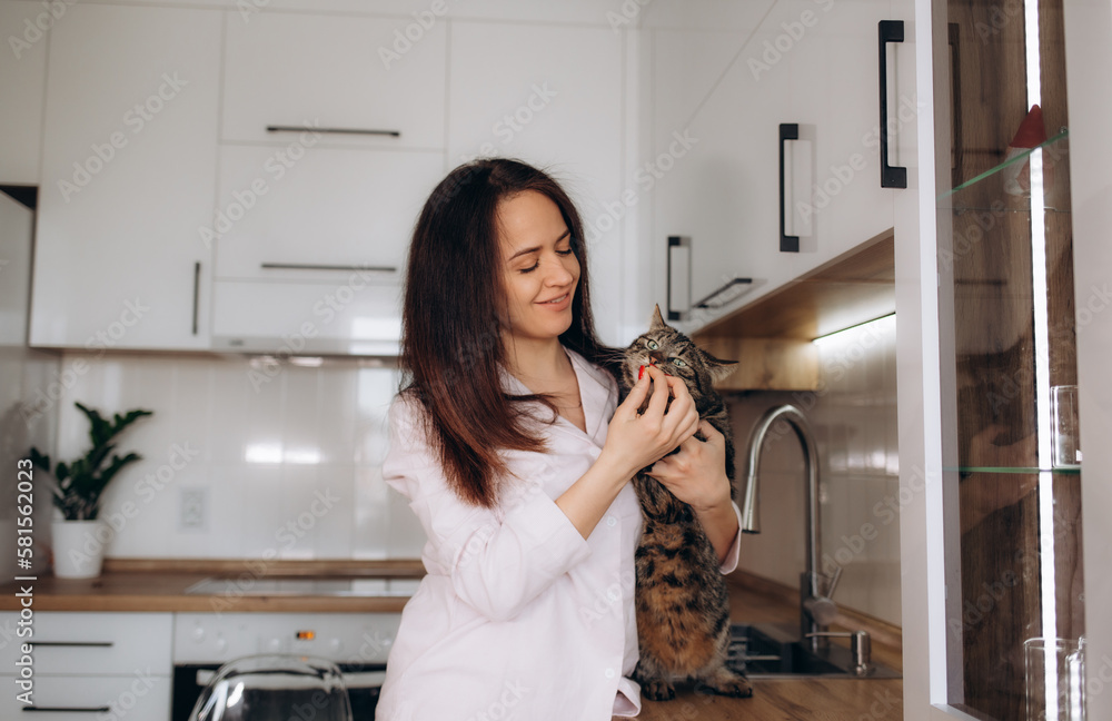 Beautiful young woman feeding her cat at home Beautiful young woman feeding her cat at home