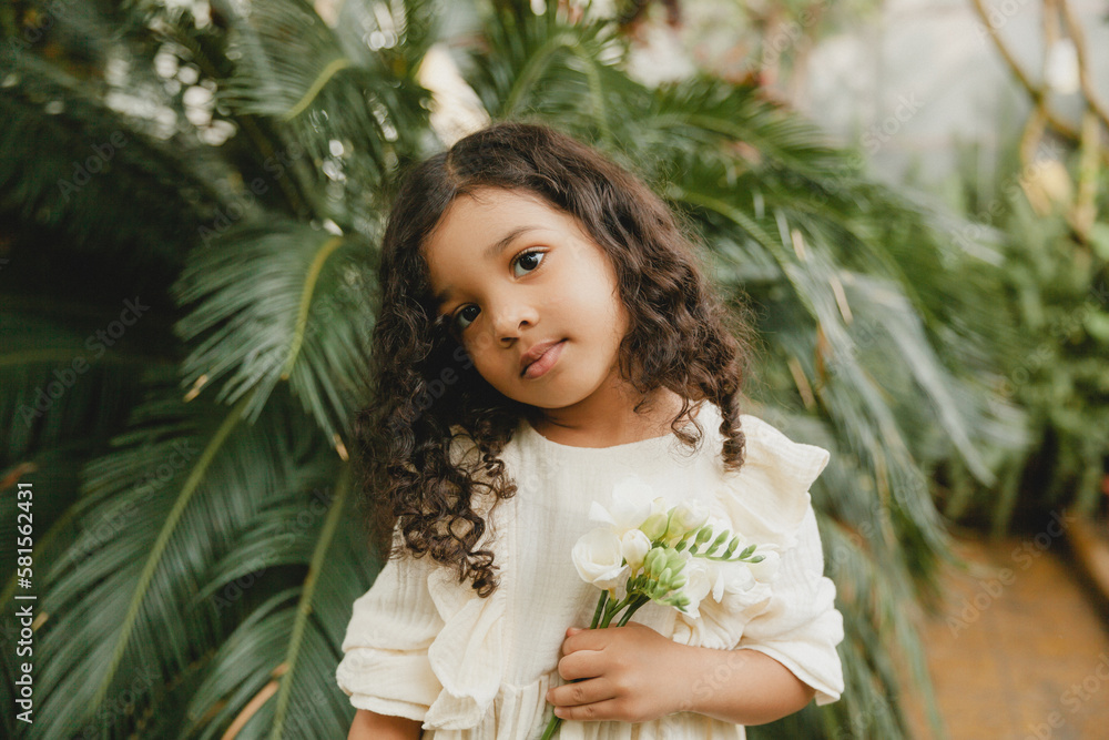 little girl surrounded by tropical leaves. Portrait of a swarthy child with dark hair. Natural cosmetics, health, cleanliness little girl surrounded by tropical leaves. Portrait of a swarthy child with dark hair. Natural cosmetics, health, cleanliness