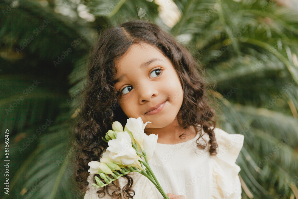 little girl surrounded by tropical leaves. Portrait of a swarthy child with dark hair. Natural cosmetics, health, cleanliness little girl surrounded by tropical leaves. Portrait of a swarthy child with dark hair. Natural cosmetics, health, cleanliness