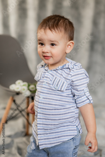 cute baby boy in jeans and shirt on a gray background in the studio