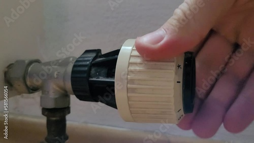 Close up of a person turning the valve of a radiator.
