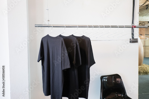 Blank T-shirt hanging on wooden clothes hanger in clothing rack.