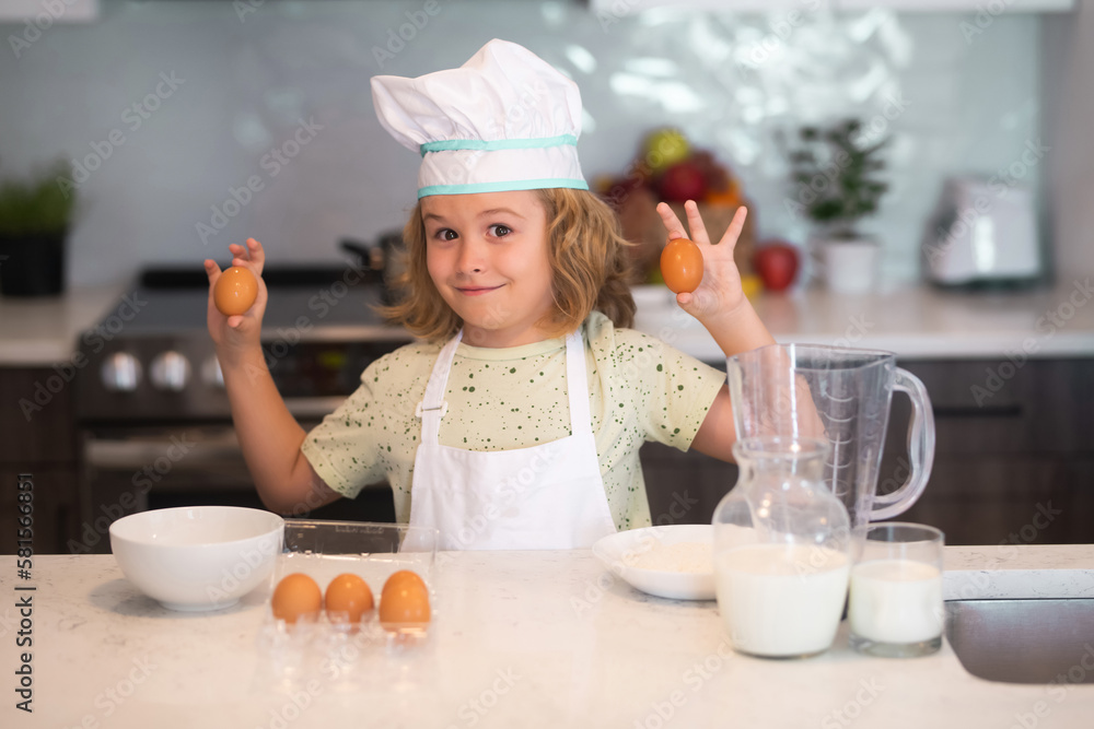 Kid chef cook with eggs at kitchen. Child chef cook prepares food at kitchen. Kids cooking. Teen boy with apron and chef hat preparing a healthy meal. Kid chef cook with eggs at kitchen. Child chef cook prepares food at kitchen. Kids cooking. Teen boy with apron and chef hat preparing a healthy meal.