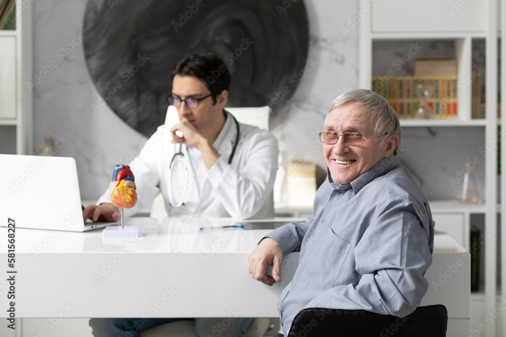Obraz premium Portrait of a smiling elderly man sitting at a table on examination by a cardiologist