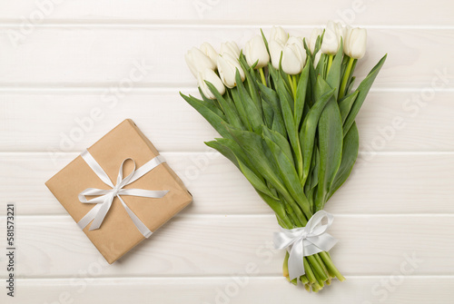 White tulip bouquet with gift box on wooden background  top view