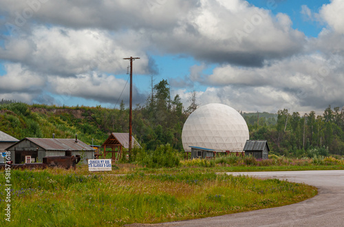 Goldstream, Alaska, USA - July 26, 2011: Farmstead in green environment with white large globe-shaped barn and Canada gas promotion board under blue cloudscape photo