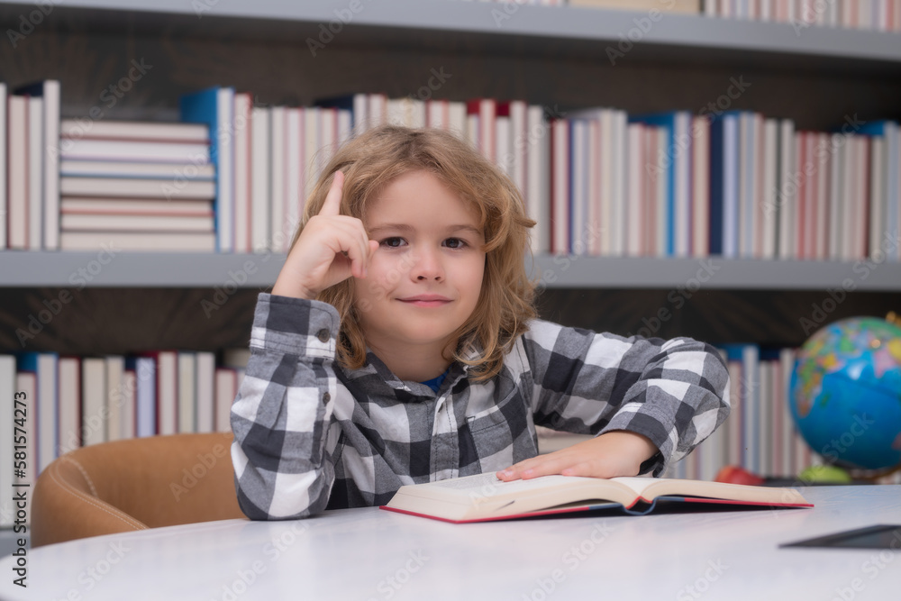 Kid reading a book in a school library. School boy education concept. Kid reading a book in a school library. School boy education concept.