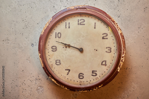 Silver chrome shiny white clock with a black arrow wall clock hangs on the concrete wall background. Simple retro loft-style design and retro decoration background. Concept timing management.