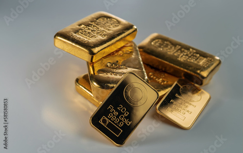 Several gold bars of different weight on a grey background. Selective focus.