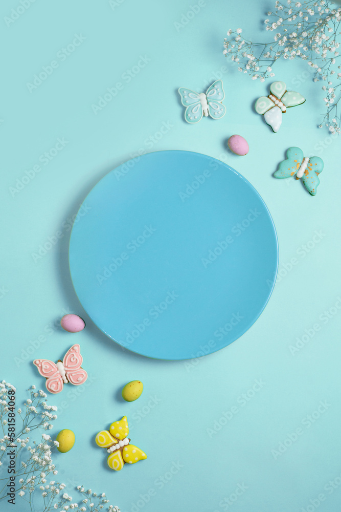 Easter banner on a blue background. Empty blue plate for text, Easter eggs and cookies in the shape of a rabbit and a butterfly. Easter concept.