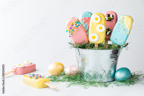 Easter themed cakesicles in a tin pail against a light background. photo