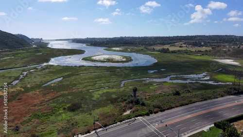 aerial footage of Batiquitos Lagoon surrounded by lush green trees and plants with blue sky and clouds and palm trees in Carlsbad California USA photo