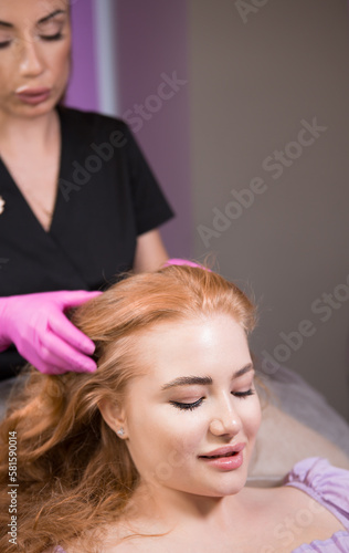 Beautician in a beauty salon makes a scalp massage to strengthen and grow hair. Mesotherapy for hair growth.
