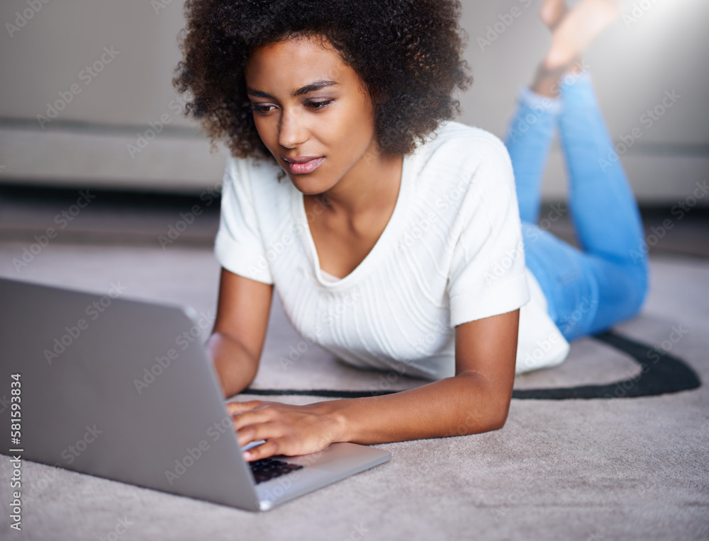 Creating some new content for her website. a young woman using her laptop while lying on the floor at home. Creating some new content for her website. a young woman using her laptop while lying on the floor at home.