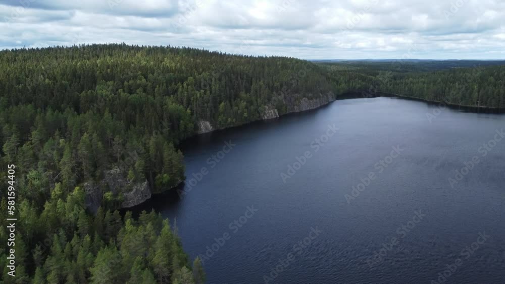 Flight forward over a lake with rocky shore in wooded wilderness in Finland Flight forward over a lake with rocky shore in wooded wilderness in Finland