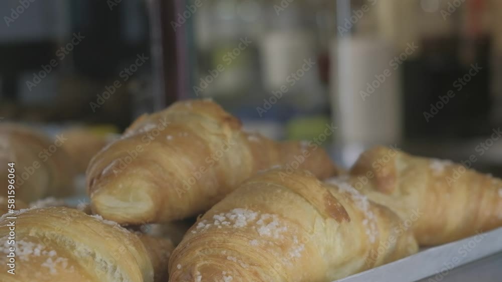 a blurry waitress' hand takes a croissant from a tray to serve it to a customer a blurry waitress' hand takes a croissant from a tray to serve it to a customer