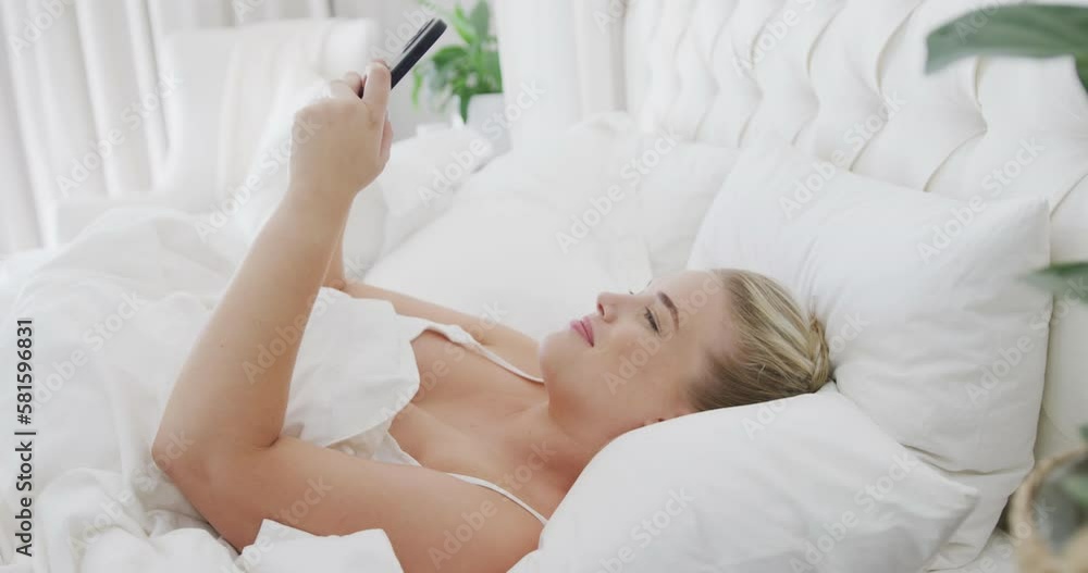 Happy caucasian plus size woman using smartphone in bed in slow motion Happy caucasian plus size woman using smartphone in bed in slow motion