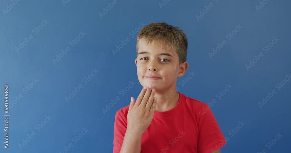 Portrait of happy caucasian boy using sign language on blue background, slow motion Portrait of happy caucasian boy using sign language on blue background, slow motion
