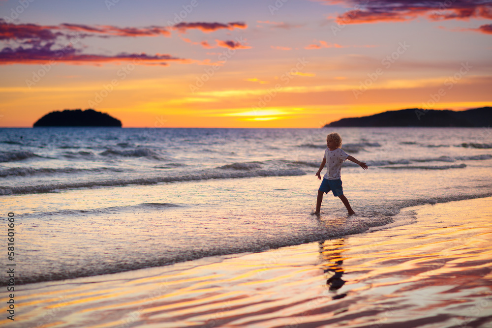 Child playing on ocean beach. Kid at sunset sea.