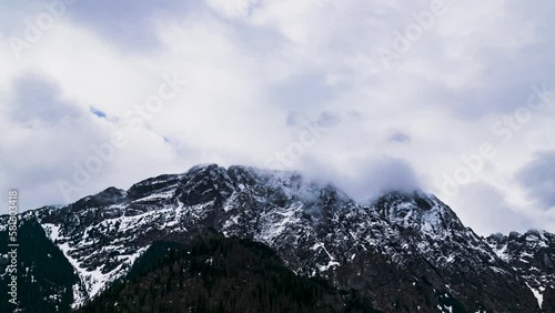 Mt. Giewont in the Polish Tatra Mountains with visible metal cross on the top against the background of an overcast sky with low clouds