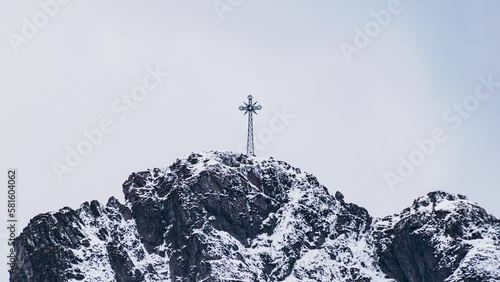 Metal cross on the top of Mt. Giewont in the Polish Tatra Mountains against the background of an overcast sky with low clouds
