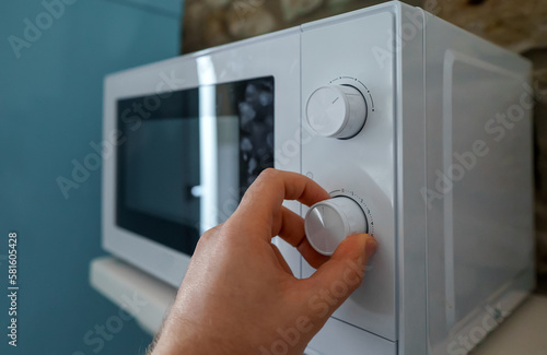 Man uses a microwave oven in the kitchen.
