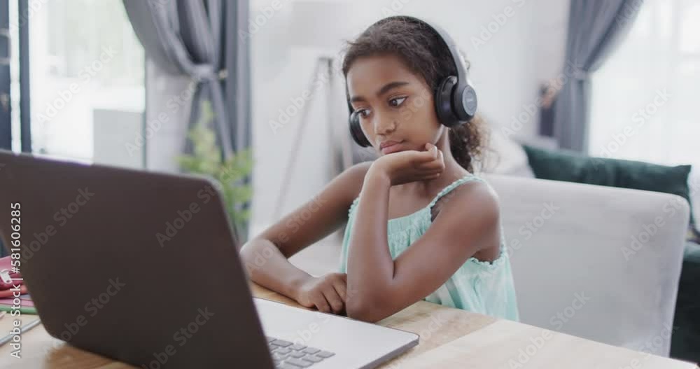 African american girl sitting at table, using laptop for online lesson, slow motion African american girl sitting at table, using laptop for online lesson, slow motion