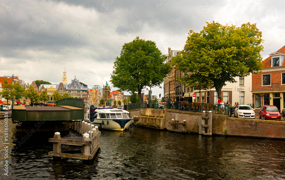 View of Catharijnebrug swing bridge over Spaarne river with passing boats in center of Dutch city of Haarlem on cloudy summer day