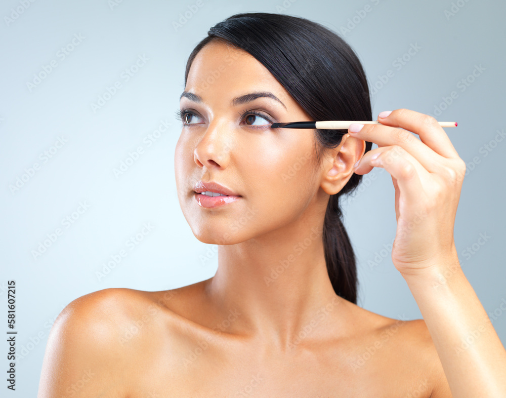 Drawing focus to her beautiful eyes. Cropped studio shot of a beautiful young woman applying eye makeup. Drawing focus to her beautiful eyes. Cropped studio shot of a beautiful young woman applying eye makeup.
