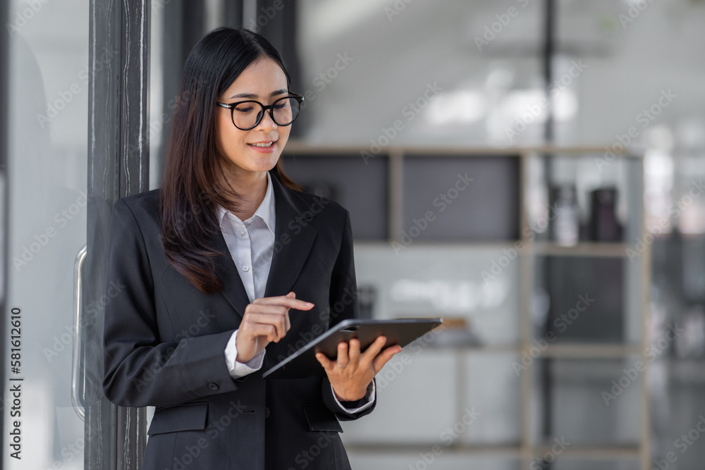 Portrait of Young business asian woman using tablet, standing in office.
