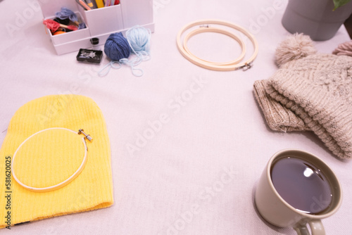 Yellow wool hat, wool yarn, embroidery hoop, coffee cup, tools