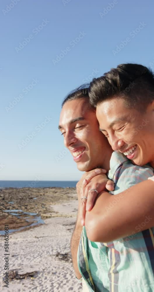 Vertical video of diverse male couple embracing at promenade by the sea, slow motion Vertical video of diverse male couple embracing at promenade by the sea, slow motion