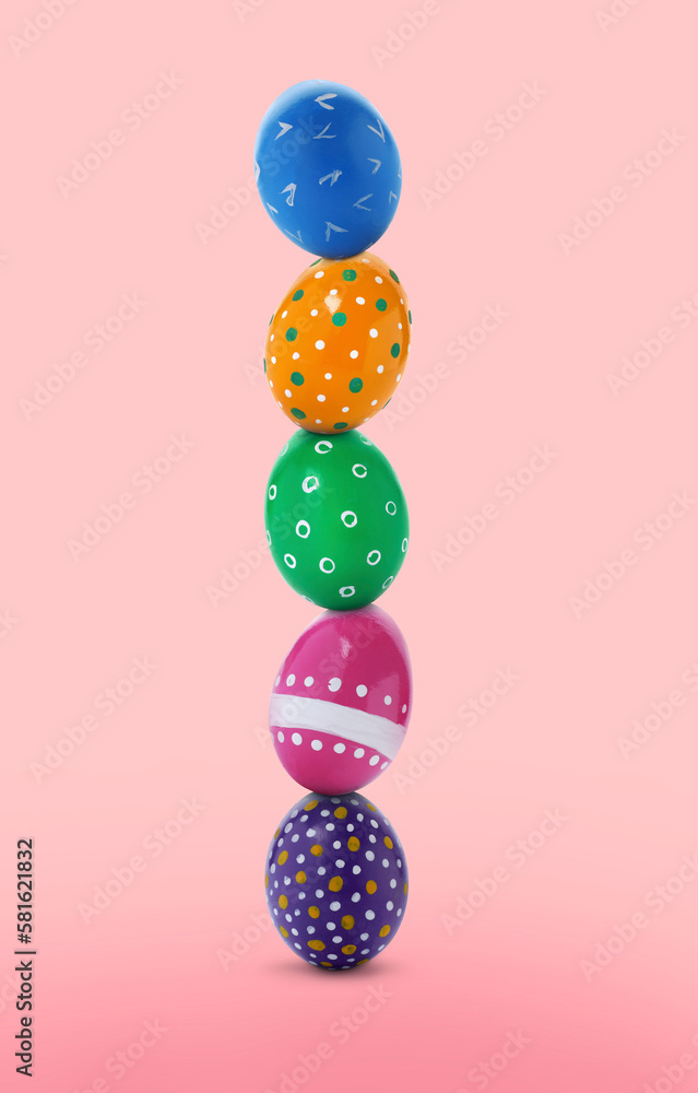 Stack of bright Easter eggs on pink gradient background