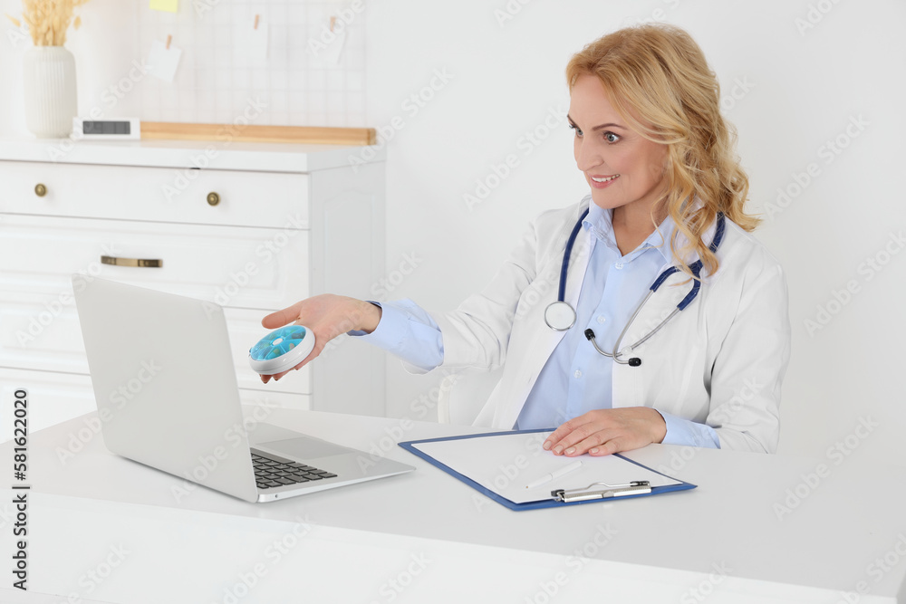 Doctor with laptop and pills consulting patient in clinic. Online medicine concept Doctor with laptop and pills consulting patient in clinic. Online medicine concept