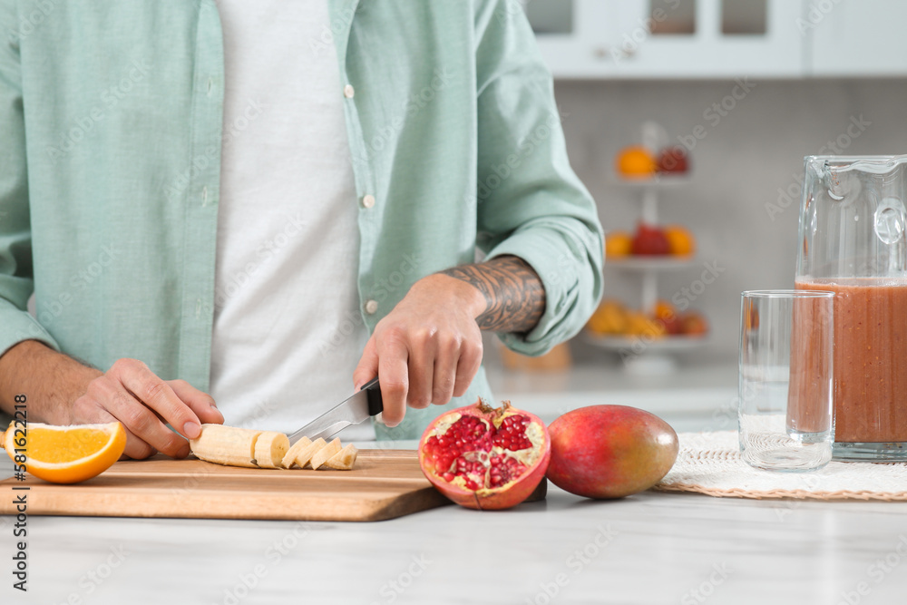 Man preparing ingredients for tasty smoothie at white marble table in kitchen, closeup
