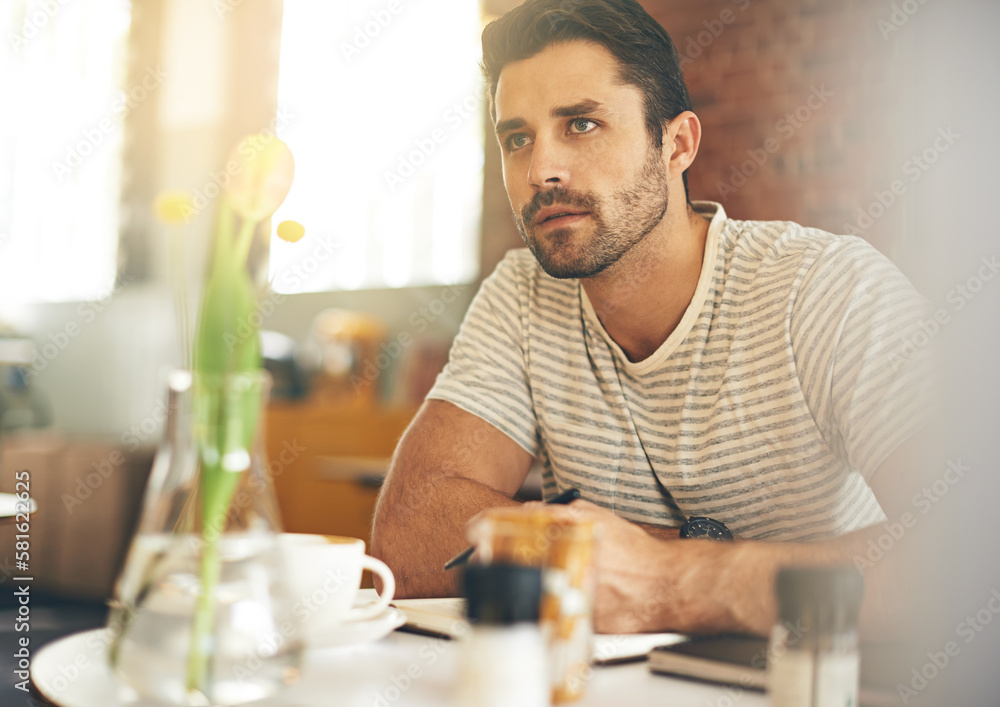 Finding inspiration at a buzzing cafe. A young man looking thoughtful while sitting in a coffee shop. Finding inspiration at a buzzing cafe. A young man looking thoughtful while sitting in a coffee shop.