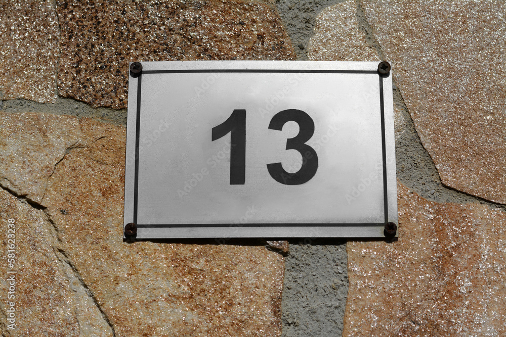 Plate with number 13 on textured stone wall, closeup Plate with number 13 on textured stone wall, closeup