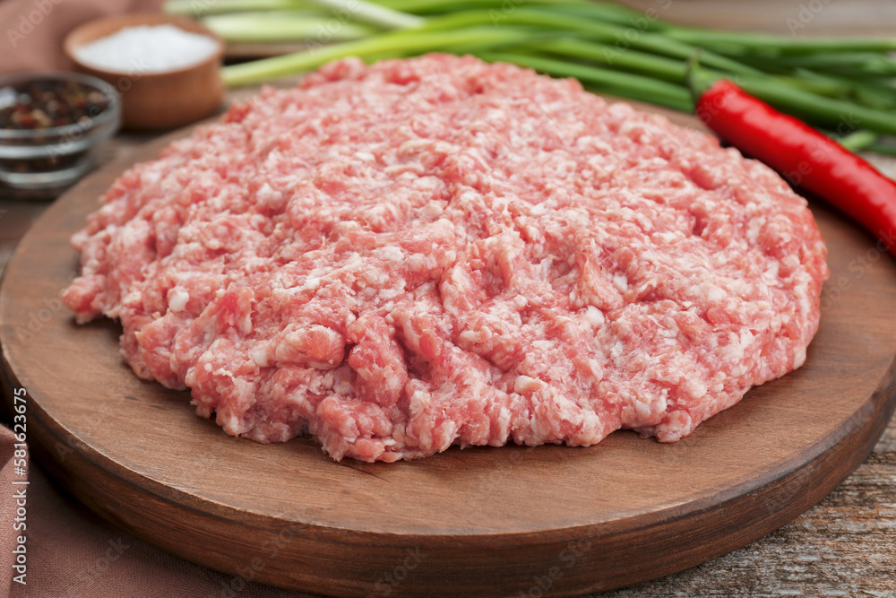Board with raw fresh minced meat on wooden table, closeup Board with raw fresh minced meat on wooden table, closeup