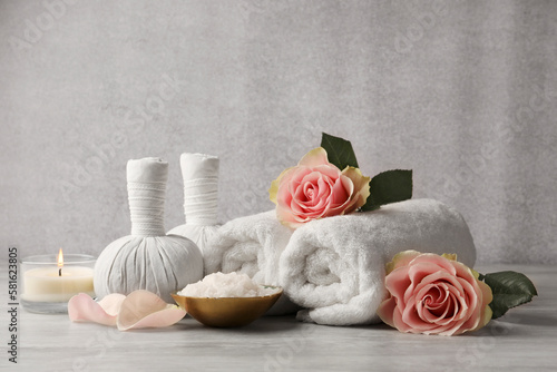 Composition with spa products, roses and candle on grey wooden table