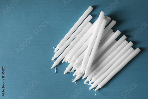 Many church wax candles on light blue background  flat lay and space for text