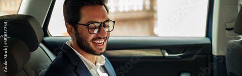 Attractive businessman in suit use phone and working laptop while riding in car to office © Kostiantyn